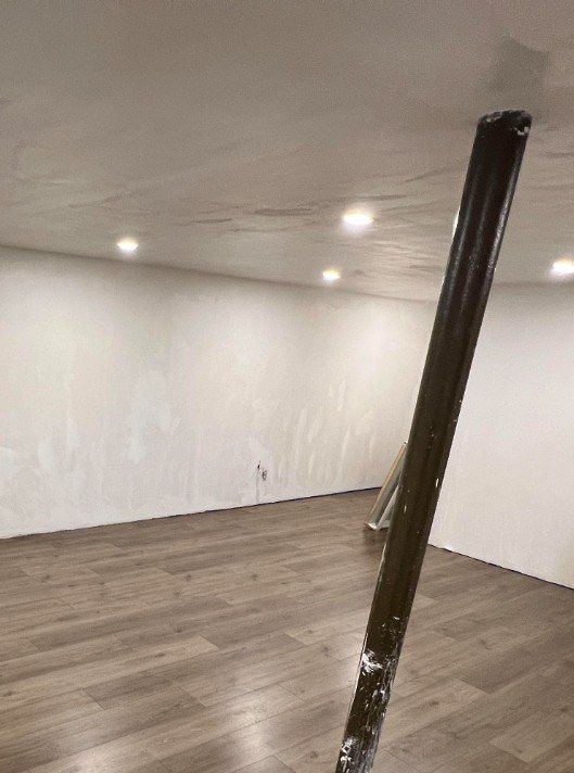 Before: basement finishing with new flooring and wrapped column