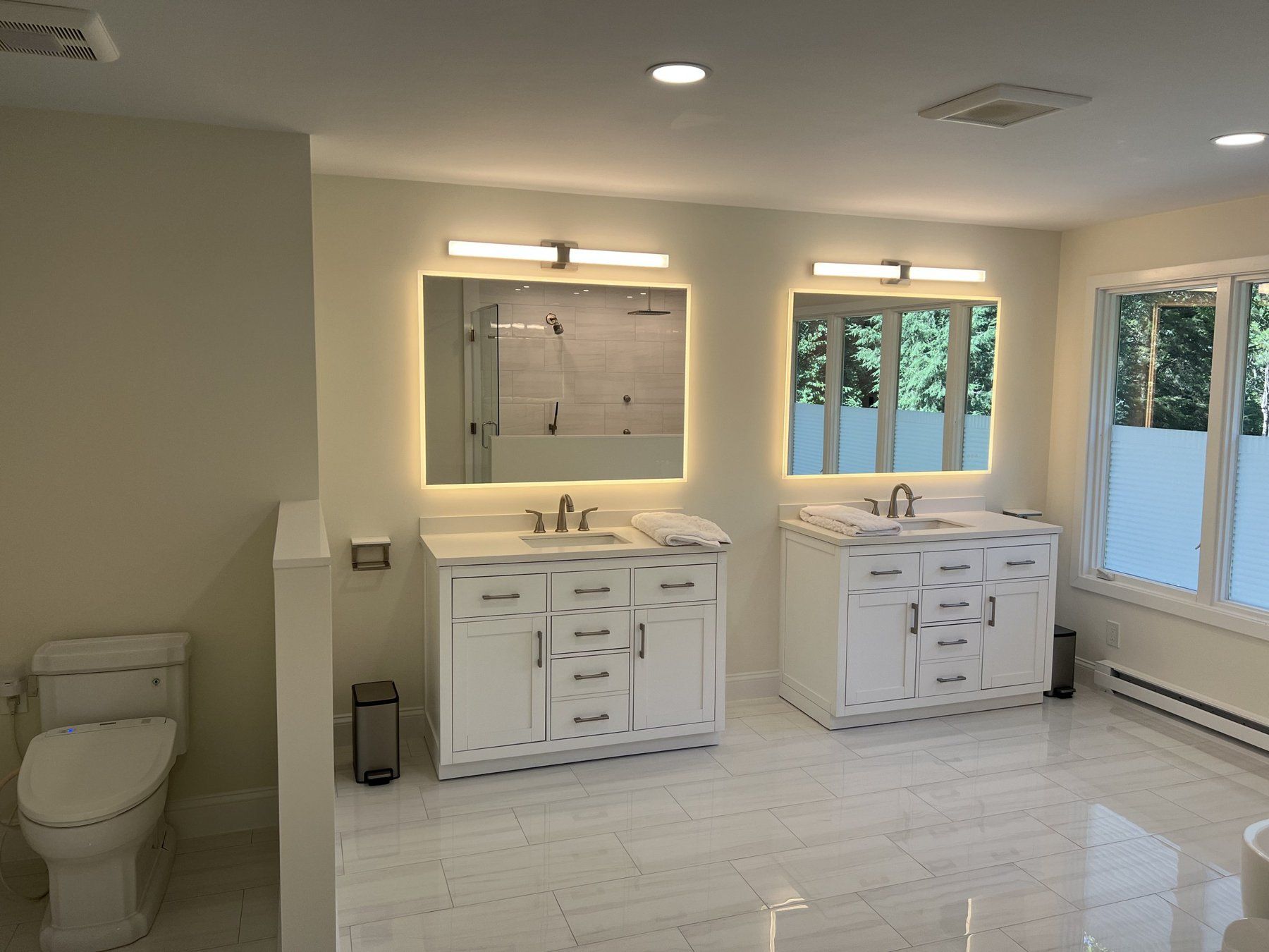 Double vanity with backlit mirrors and glossy porcelain floor tile, bathroom remodel in Marlborough, MA