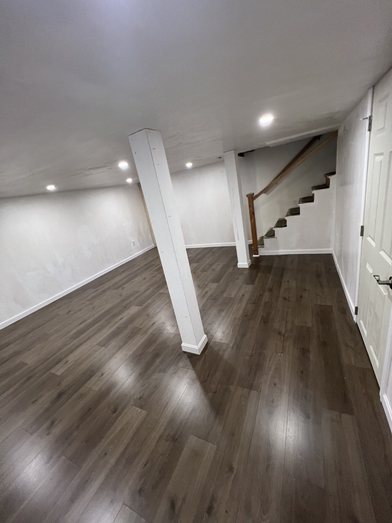 Finished basement with new stairs, wrapped columns and vinyl plank floor