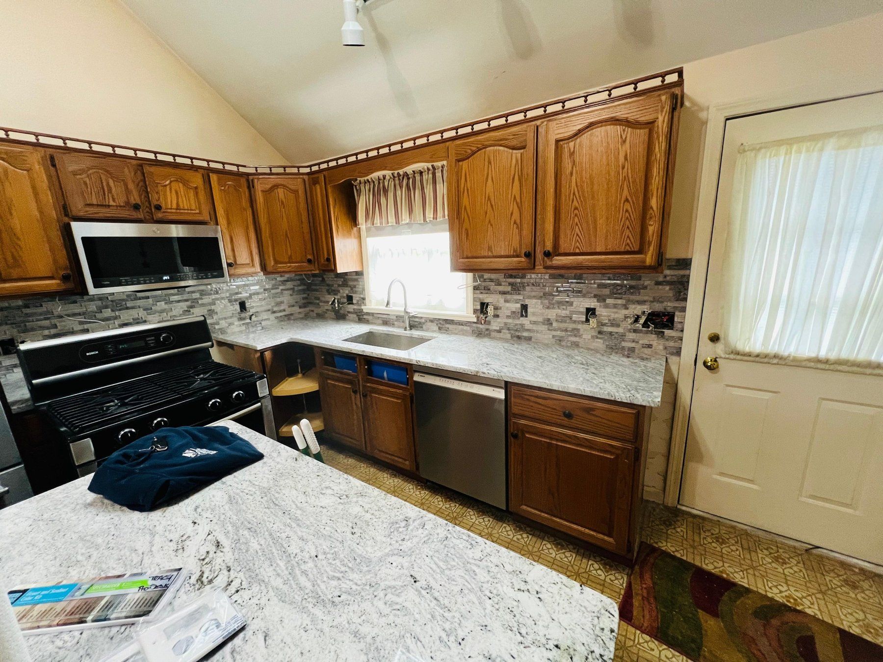 Granite countertops and tile backsplash in an oak kitchen