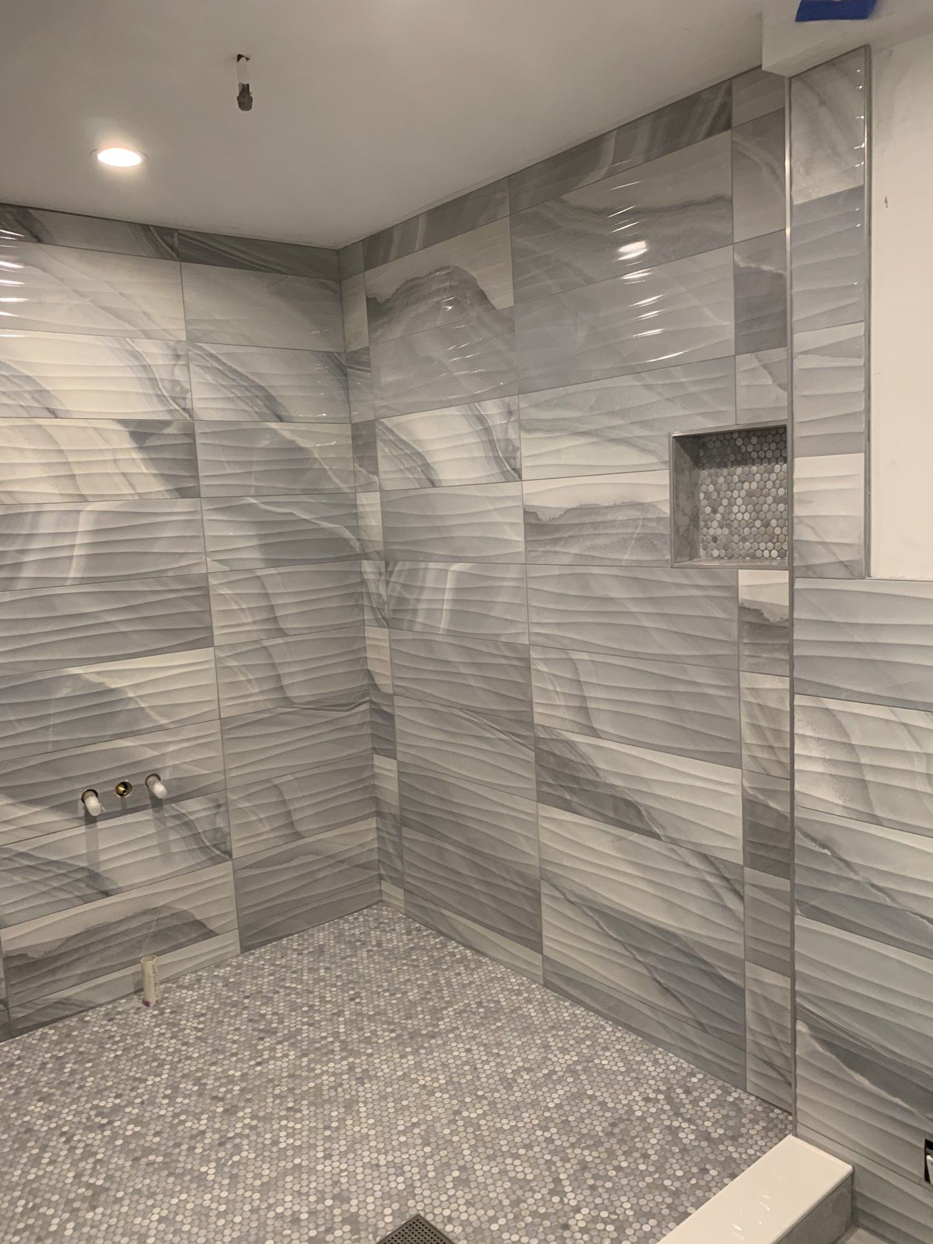 Gray porcelain shower walls with pebble mosaic floor