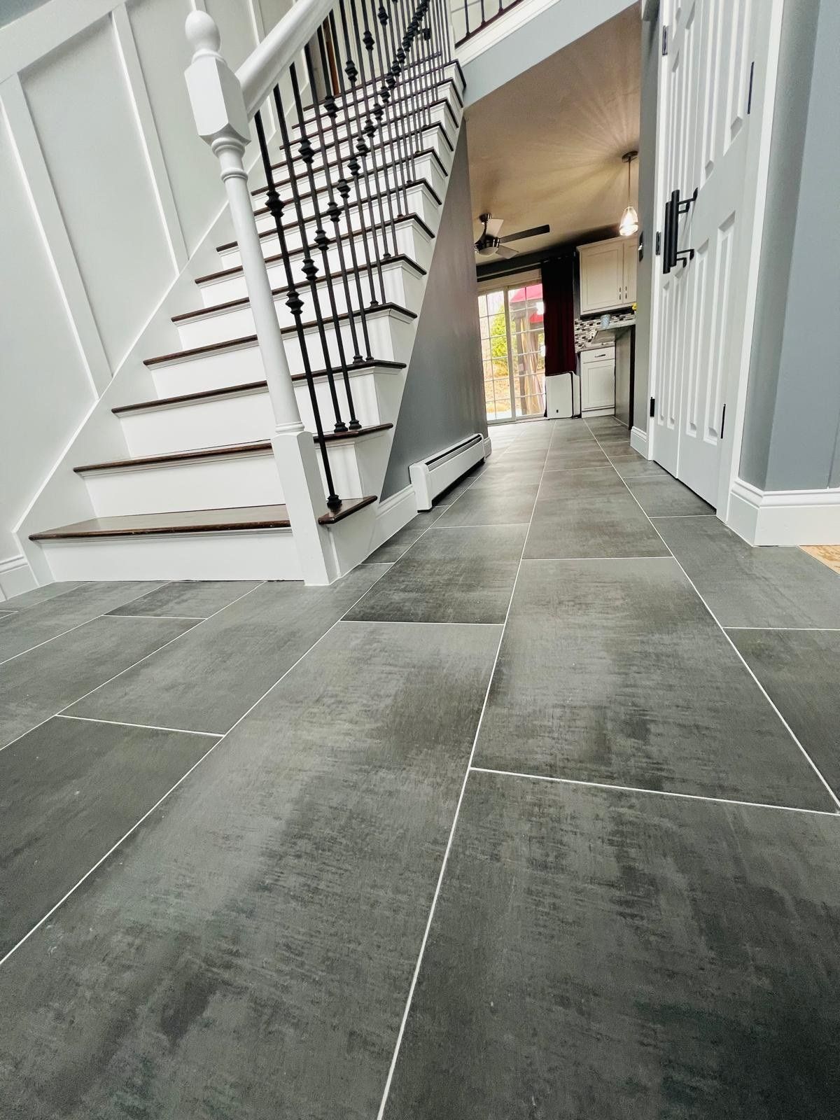 Gray porcelain tile foyer at the foot of the staircase