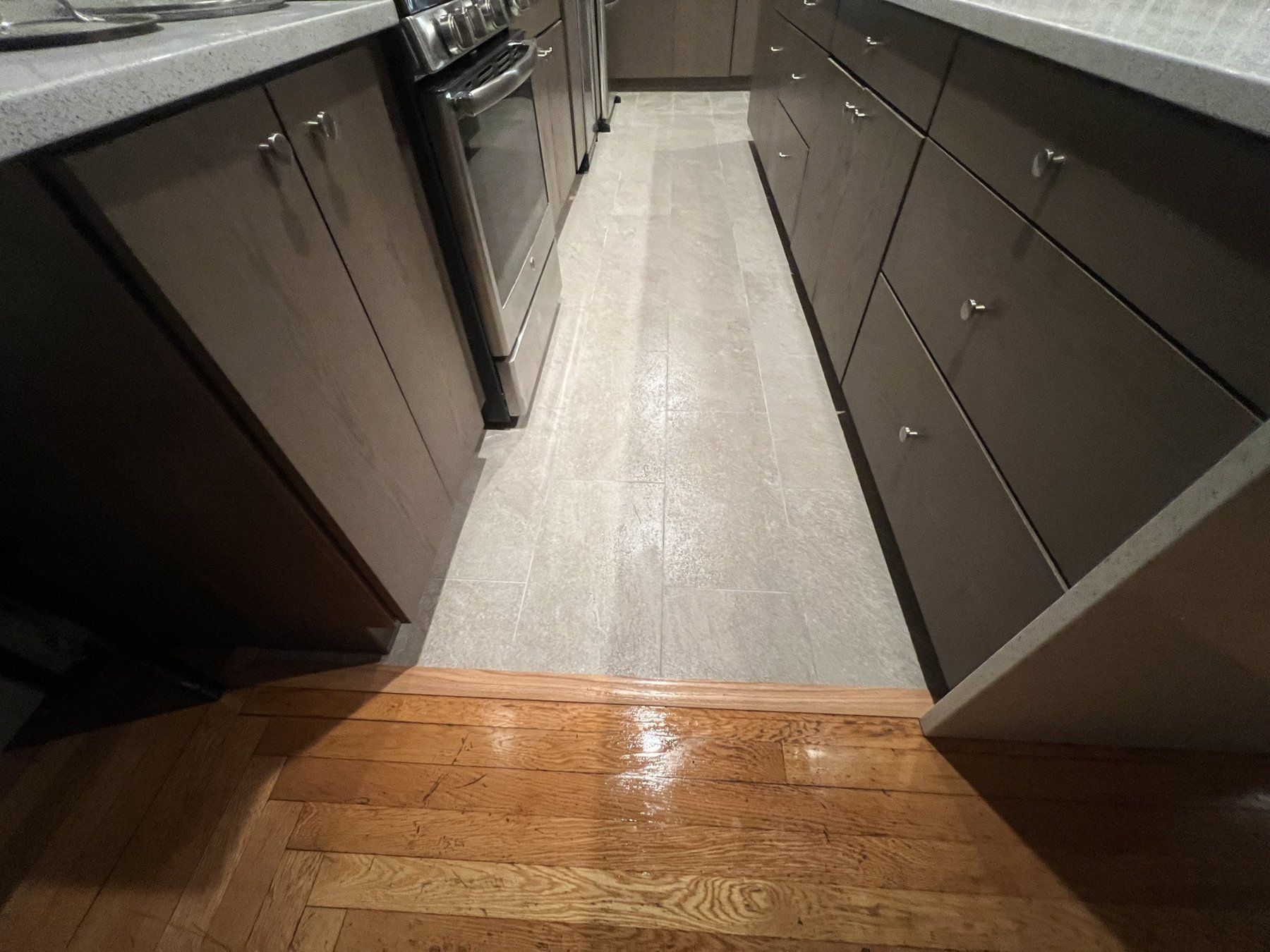Modern kitchen with porcelain tile floor between dark cabinets