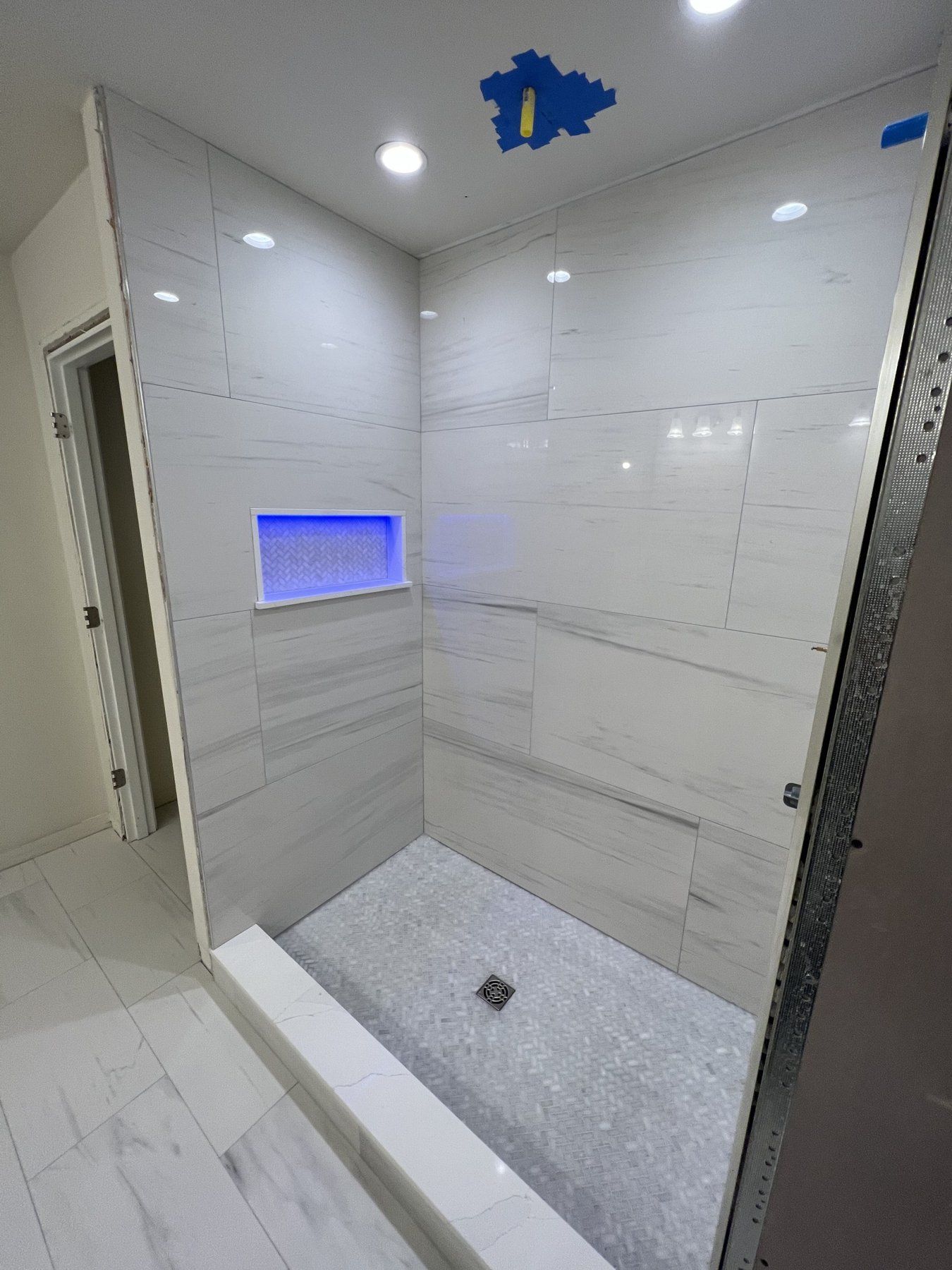 Large-format gray tile walk-in shower with lit niche and mosaic floor, bathroom remodel near Marlborough, MA