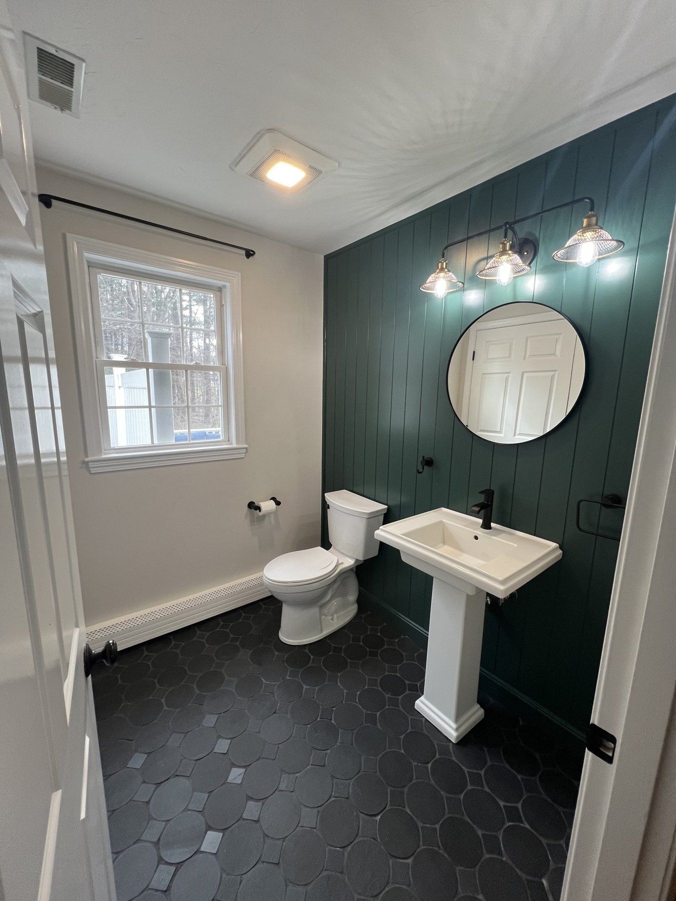 Powder room remodel with green shiplap wall, pedestal sink and black octagon floor tile