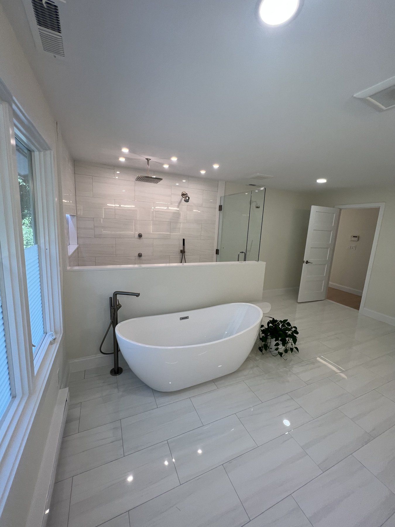 Primary bathroom remodel in Marlborough, MA with freestanding tub, frameless glass walk-in shower and large-format porcelain floor
