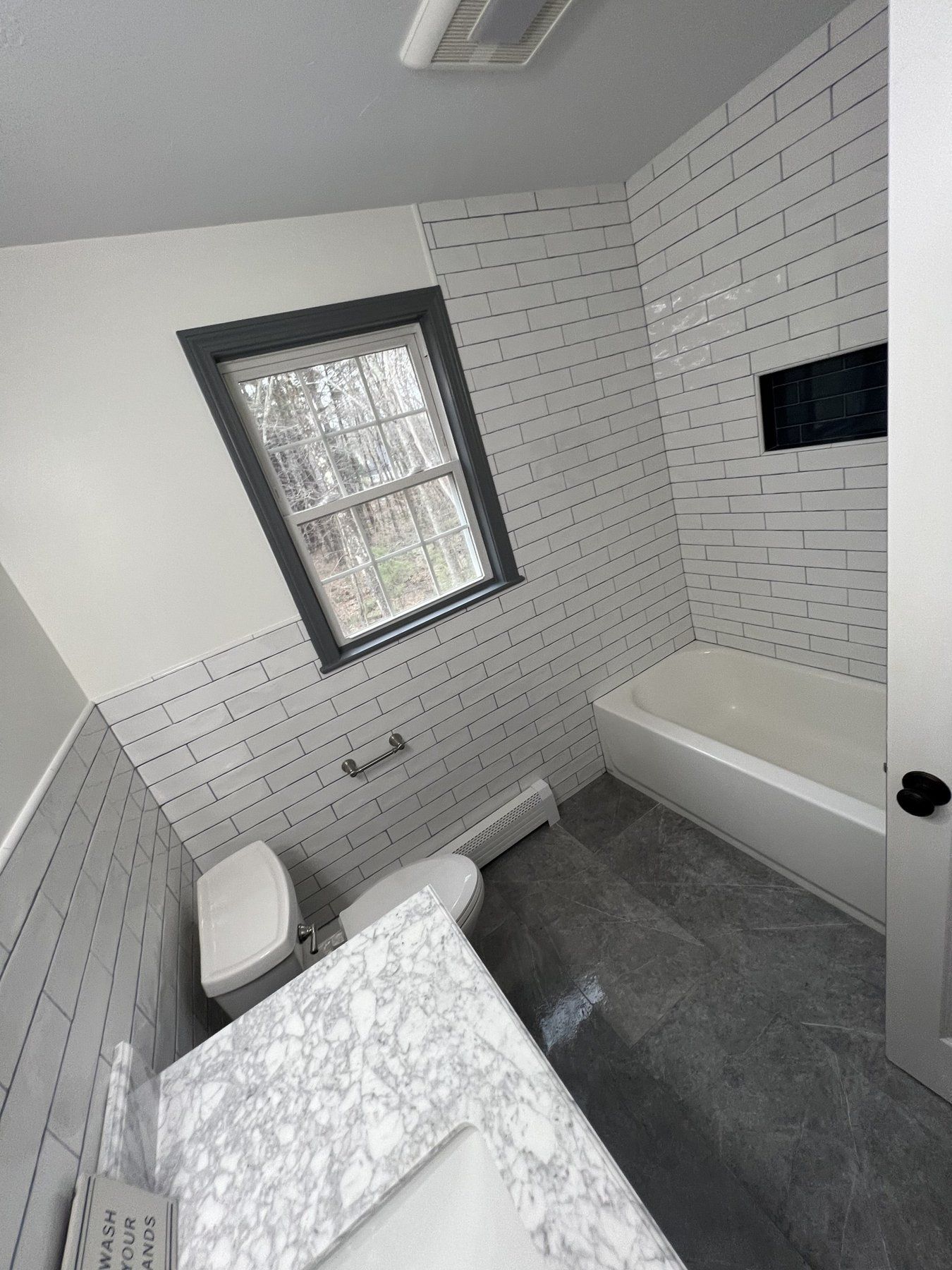 Subway tile bathroom remodel with tub, window and quartz vanity