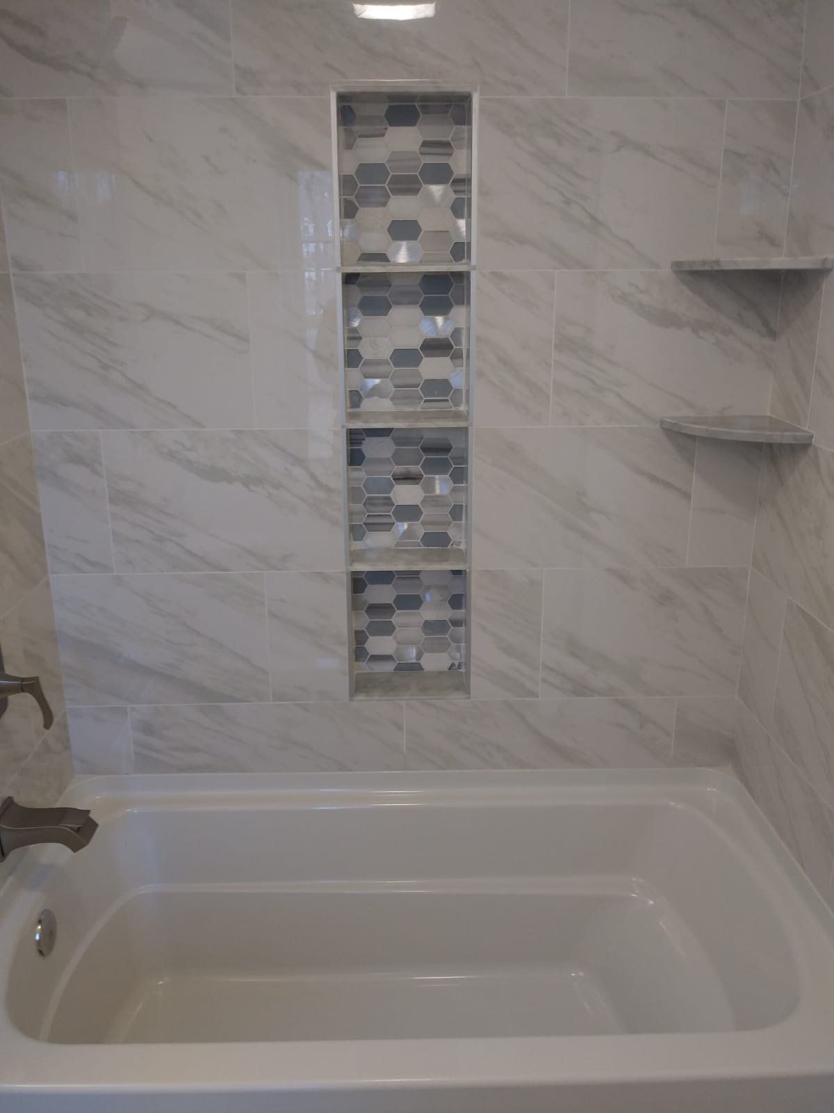 Marble-look tub surround with vertical mosaic niche and corner shelves
