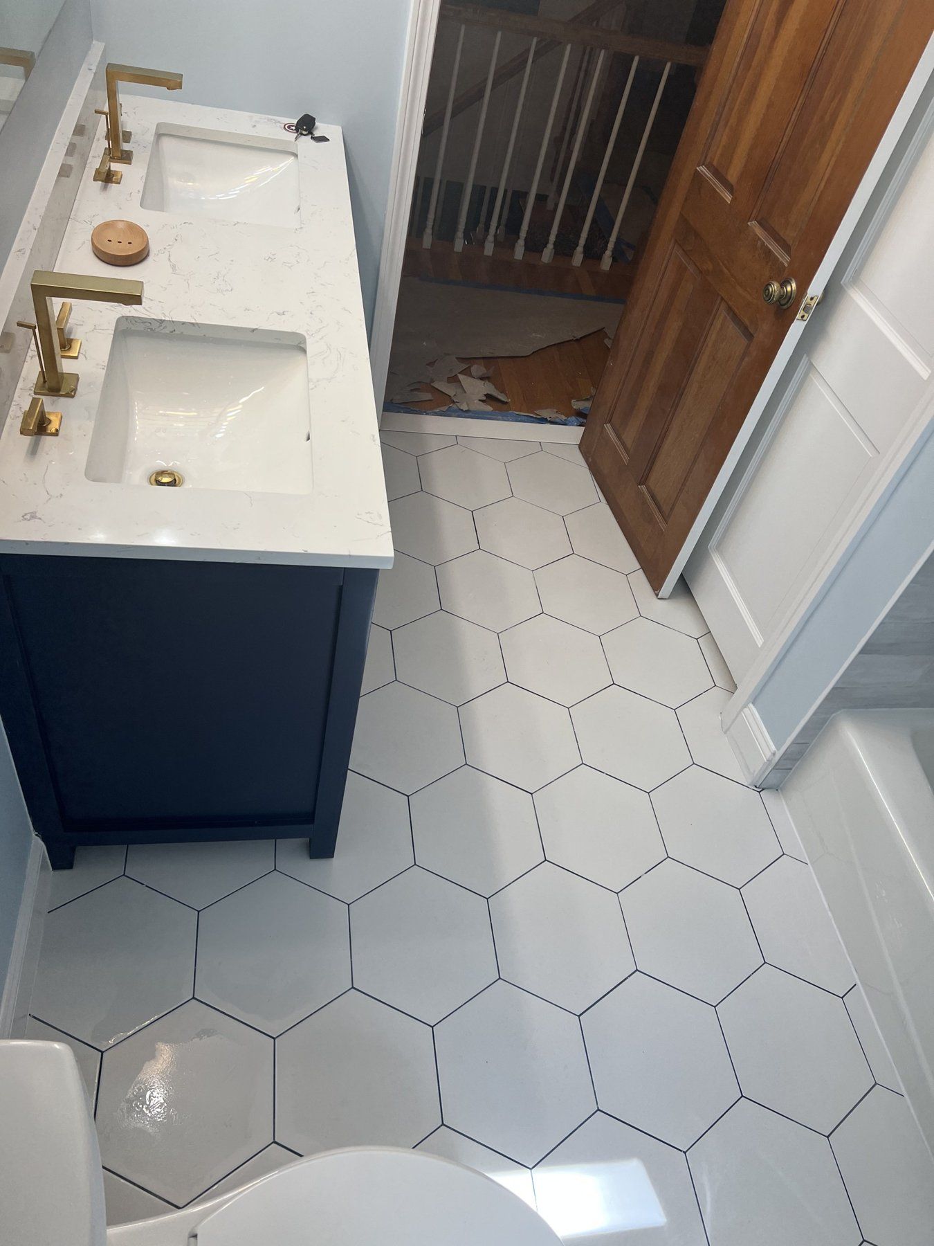 White hexagon floor tile with navy vanity and brass fixtures