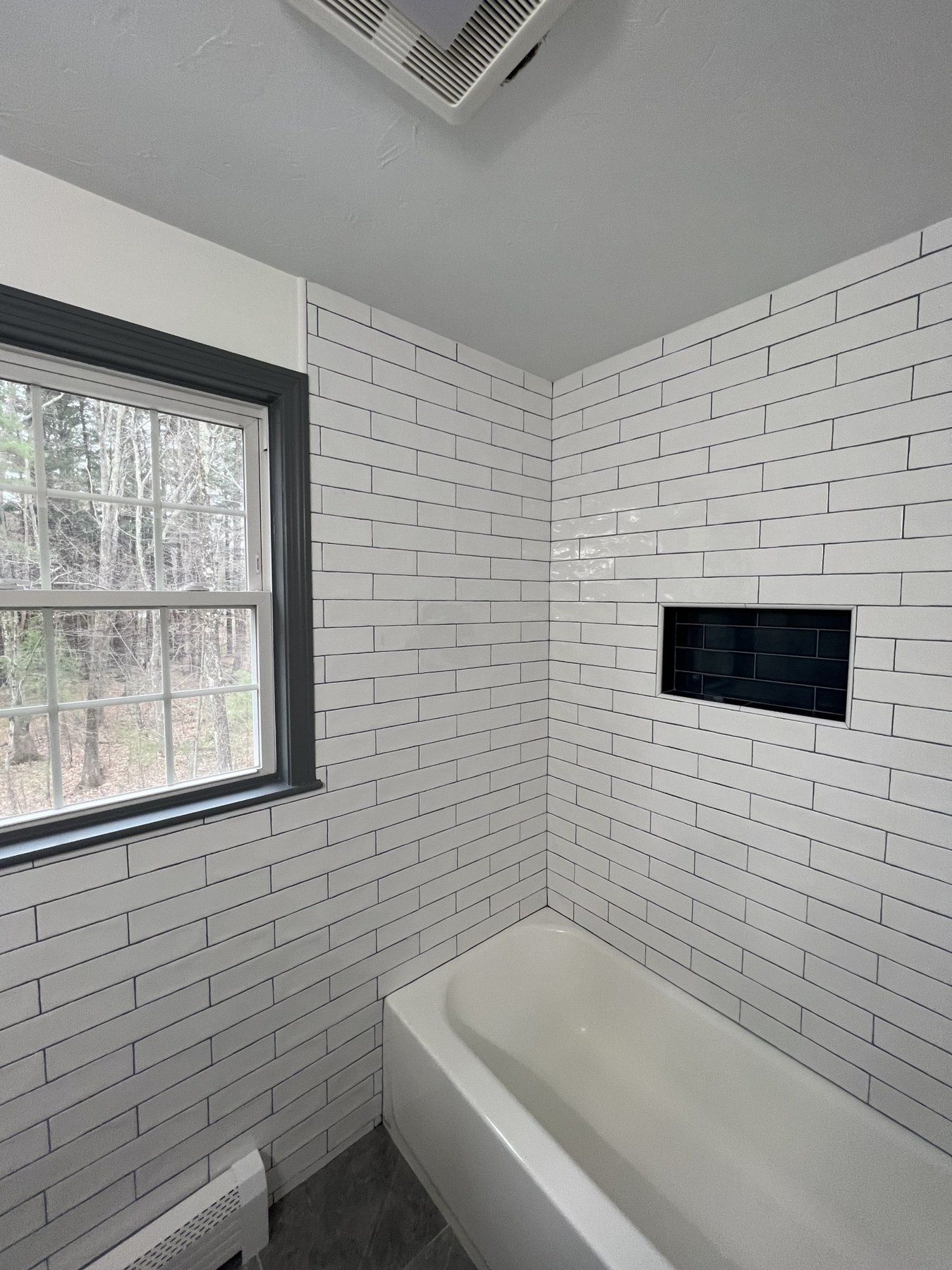 White subway tile tub surround with black niche, bathroom remodel in MetroWest Massachusetts