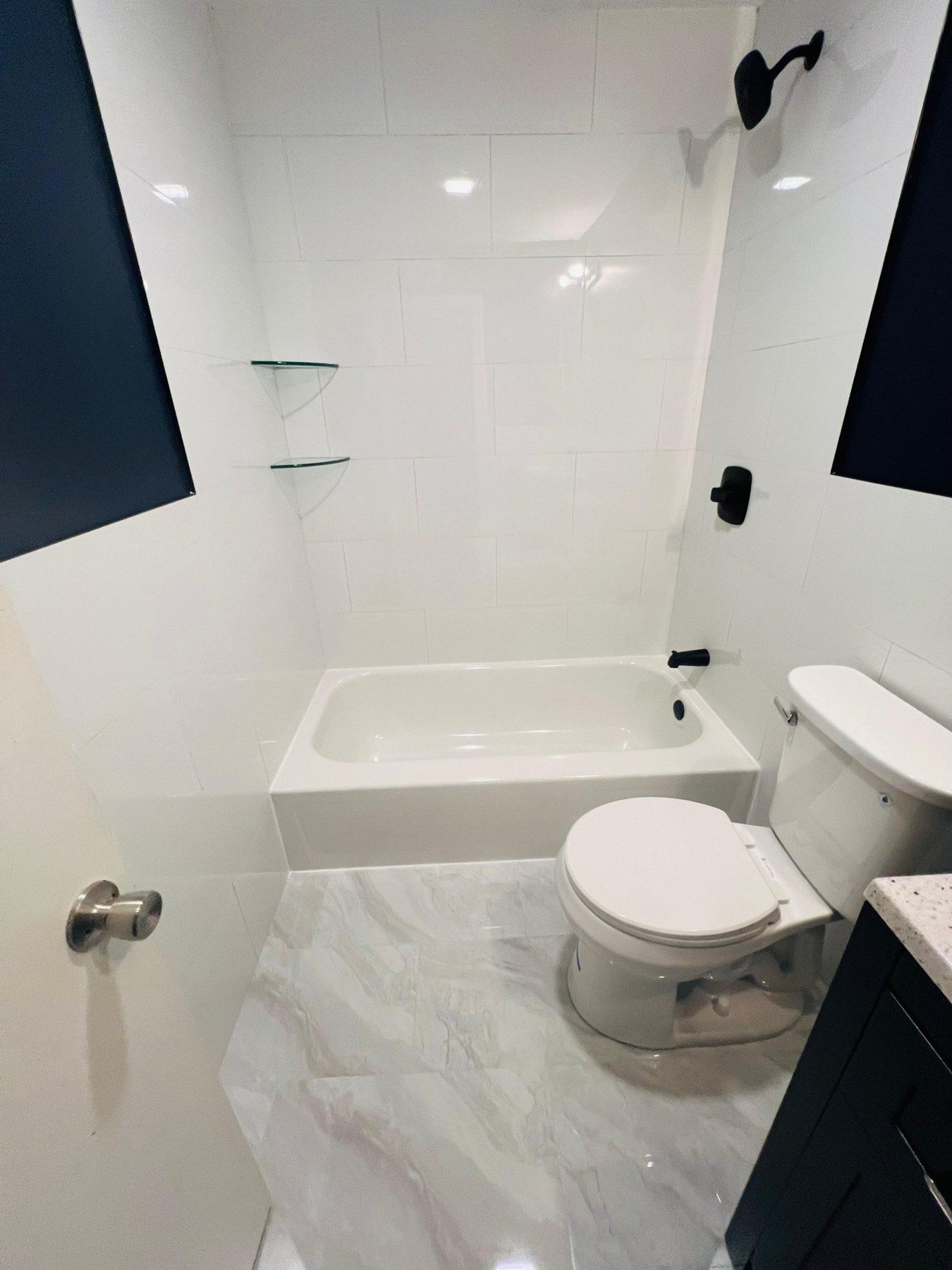 White tile tub surround with marble-look porcelain floor